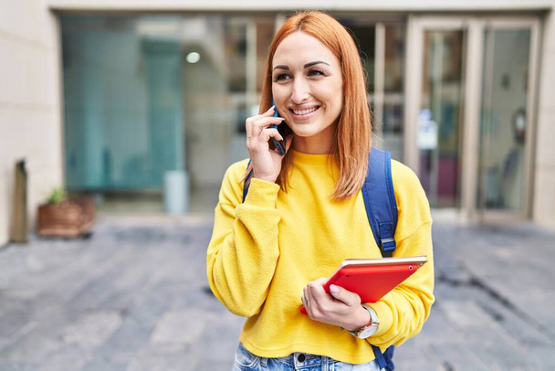 Nuori valkoihoinen nainen opiskelija hymyilee luottavainen puhuu älypuhelimeen yliopistossa - Valokuva, kuva