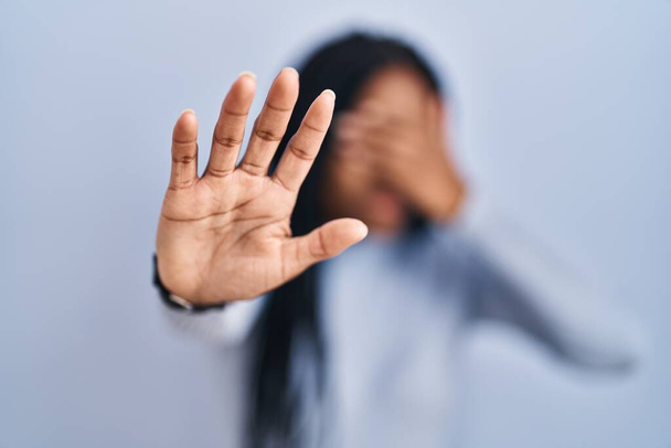 African american woman standing over blue background covering eyes with hands and doing stop gesture with sad and fear expression. embarrassed and negative concept.  - Fotoğraf, Görsel