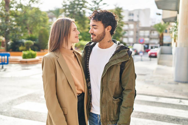 man en vrouw glimlachend zelfverzekerd knuffelen elkaar op straat - Foto, afbeelding