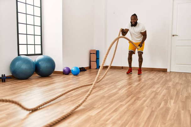 Young african american man smiling confident training with battle rope at sport center - Φωτογραφία, εικόνα