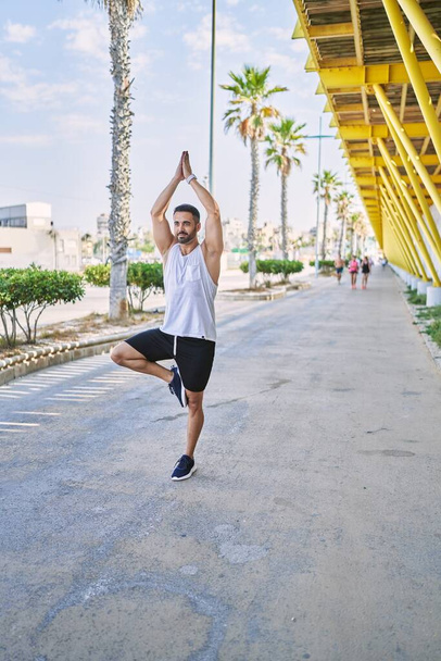 Hispanischer Mann, der an einem sonnigen Tag im Freien Yoga macht - Foto, Bild