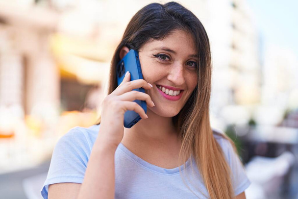 Jeune femme hispanique souriant confiant parler sur le smartphone à la rue - Photo, image
