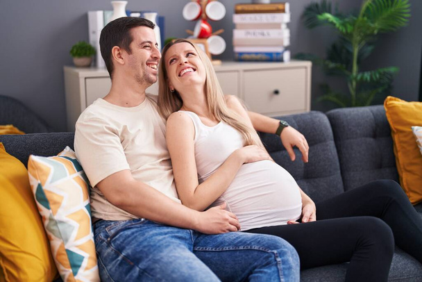 Man and woman couple expecting baby hugging each other at home - Photo, Image