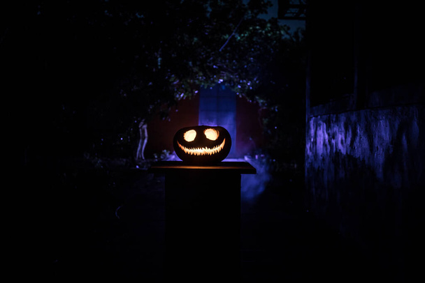 Pumpkin Burning In Forest at night. Abandoned building in forest. Scary Jack o Lantern smiling and glowing pumpkin with dark toned foggy background. Selective focus - Photo, Image