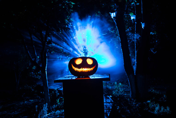 Pumpkin Burning In Forest at night. Scary Jack o Lantern smiling and glowing pumpkin with dark toned foggy background. Selective focus - Photo, Image