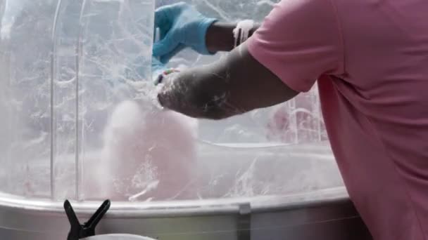 Zbliżenie kobiecych rąk kręcących kijem w maszynie do waty cukrowej na jesiennym festiwalu.  - Materiał filmowy, wideo