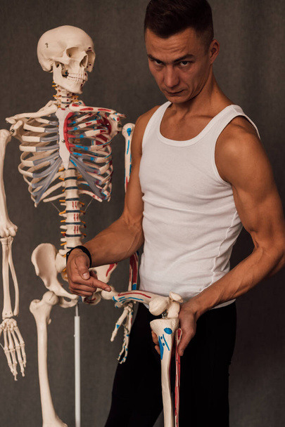 een man houdt een skelet been in zijn handen en wijst er een vinger naar. Hoge kwaliteit foto - Foto, afbeelding