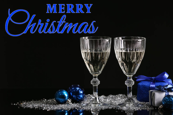 Ευχετήρια κάρτα με ποτήρια σαμπάνιας, χριστουγεννιάτικα στολίδια και κουτιά δώρων σε σκούρο φόντο - Φωτογραφία, εικόνα