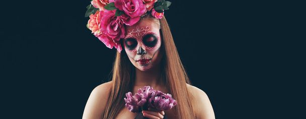 Fiatal nő festett koponya az arcán a mexikói Day of the Dead (El Dia de Muertos) sötét háttér - Fotó, kép