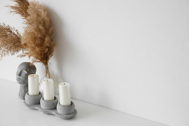 Stylish holder with candles and decor on table near white wall - Photo, Image