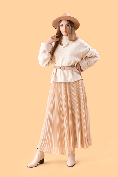 Belle jeune femme à la mode en vêtements d'automne sur fond beige - Photo, image