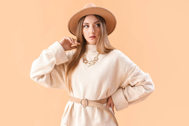 Bella giovane donna alla moda in abiti autunnali su sfondo beige - Foto, immagini