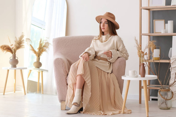 Hermosa mujer joven de moda en ropa elegante sentada en sillón en casa - Foto, imagen