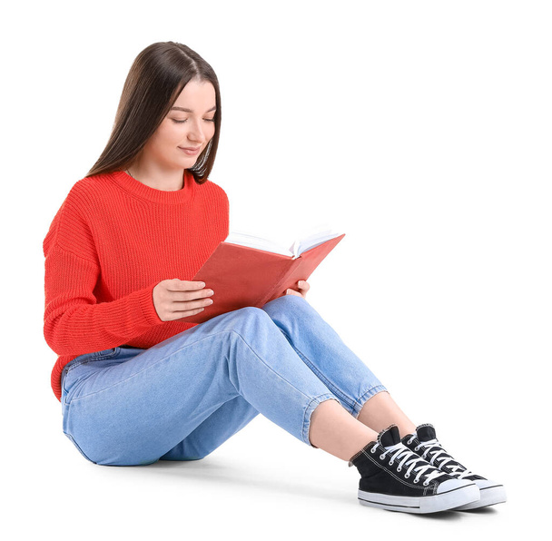 Young woman in red sweater reading book on white background - Fotó, kép