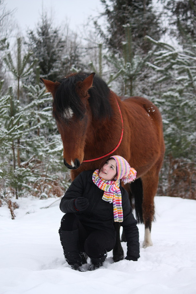 Belle adolescente assise près du cheval brun en hiver
 - Photo, image