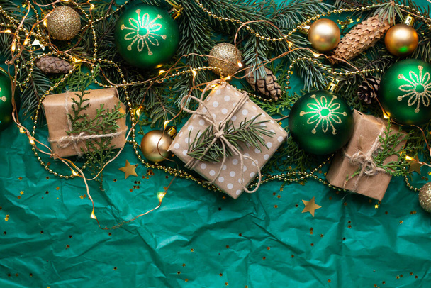 cajas de regalo en la mesa verde y ramas de abeto. caja con lazo de cinta presente en el papel envuelto de vacaciones. regalos de Navidad minimalistas y bolas - Foto, Imagen