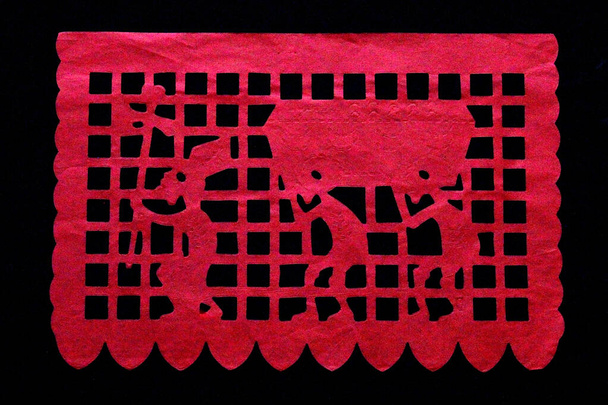 Papel picado de colores para una ofrenda a la tradición mexicana del Día de los Muertos y Todos los Santos con formas de cráneo sobre un fondo negro - Foto, Imagen