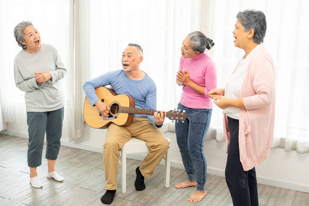Група людей похилого віку насолоджується діяльністю разом з лікарем. Літні люди мають веселу концепцію. Щасливі старшокласники грають на гітарі та співають пісні, розважаючись разом
. - Фото, зображення