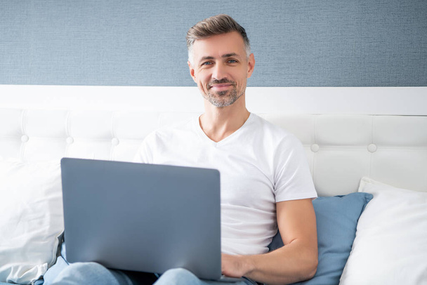 mature man buy online on laptop in bed. - Fotoğraf, Görsel