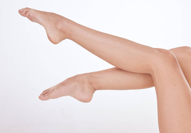 Closeup of unrecognizable woman posing against a white studio background. One female only feeling confident while showing her hairless, smooth legs after hair removal or epilation. - Foto, immagini