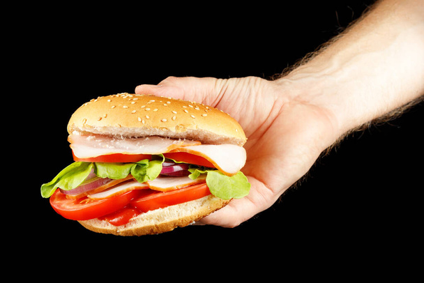 Burger na mão isolar em preto. - Foto, Imagem