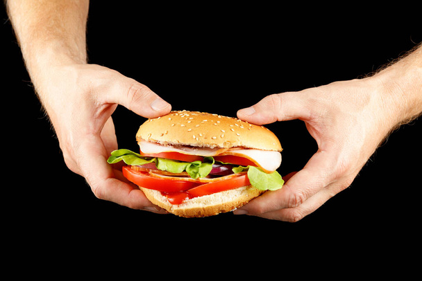 Burger in hands isolate on black. - 写真・画像