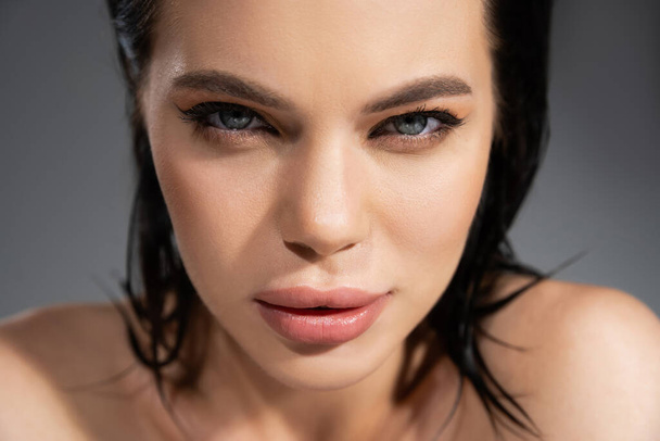 Portrait of brunette woman with makeup looking at camera isolated on grey  - Photo, Image