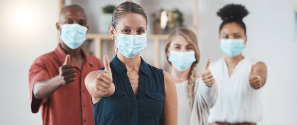 Daumen hoch, covid Pandemie und Mitarbeiter mit Maske in der Wirtschaft zeigen eine positive Einstellung am Arbeitsplatz. Coronavirus-Epidemie, Gesundheits- und Sicherheitspolitik der Mitarbeiter im Büro der Werbe- oder Marketinggesellschaft. - Foto, Bild