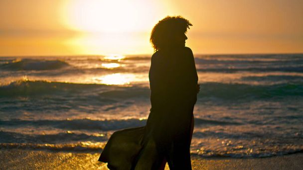 前に明るい日の出の光だけで幸せな女の子のシルエット立って海の波。海岸に黒い水着姿のフリー巻き女。陽気な笑顔の女性は夏の自然をリラックス. - 写真・画像