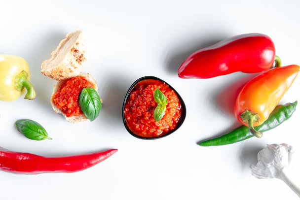 Ajvar sauce of roasted red pepper on a white background isolate with ingredients. Top view. - Photo, image