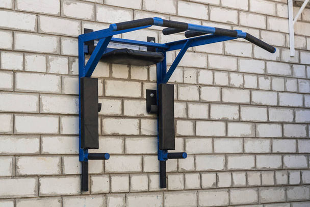 Blauwe horizontale stang voor oefeningen op een stenen muur - Foto, afbeelding