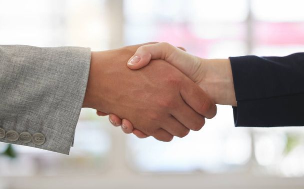 Two businesspeople shaking hands while in an office together at work. Business professionals greeting networking and making deals with each other. Boss hiring an employee. - Фото, зображення