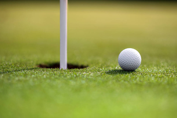 Bola branca por mastro no buraco no campo de golfe verde no dia ensolarado - Foto, Imagem