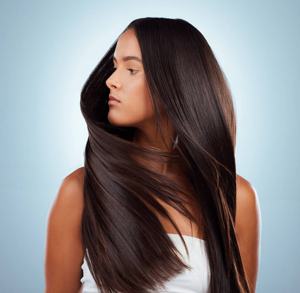 A hispanic brunette woman with long lush beautiful hair posing against a grey studio background. Mixed race female standing showing her beautiful healthy hair. - Photo, image