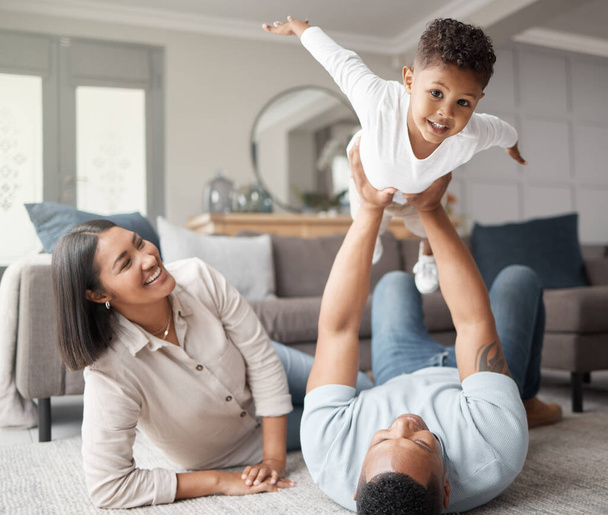 A happy mixed race family of three relaxing on the lounge floor and being playful together. Loving black family bonding with their son while playing fun games on the carpet at home. - Φωτογραφία, εικόνα