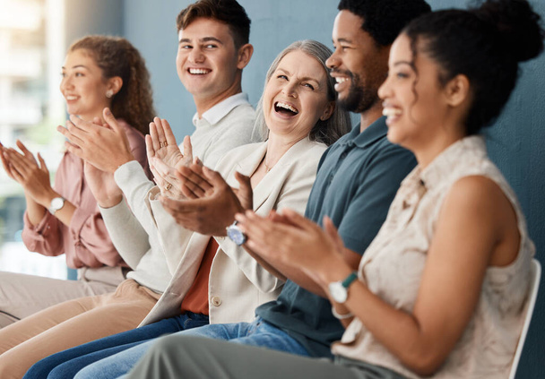 Egy csapat vidám üzletember tapsol, miközben egymás után ülnek egy megbeszélésen. Boldog üzleti szakemberek motiválják egymást, miközben együtt ülnek egy váróteremben egy irodában.. - Fotó, kép