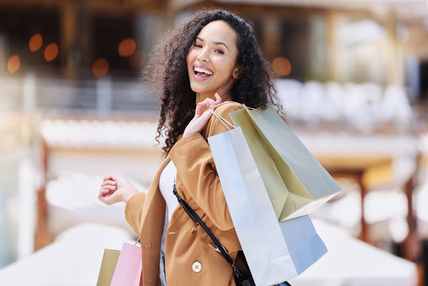 Shopping, happy and portrait of customer with bag after shopping spree buying retail fashion product on store discount. Sales, smile and young black woman at luxury shopping mall to purchase clothes. - 写真・画像