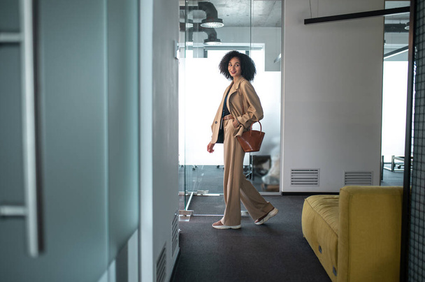 In the office. Confident and determined businesswoman entering a modern office with glass doors - Фото, изображение