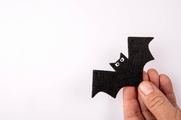 Black decorative bat with eyes in a mans hand on a white background. - Φωτογραφία, εικόνα