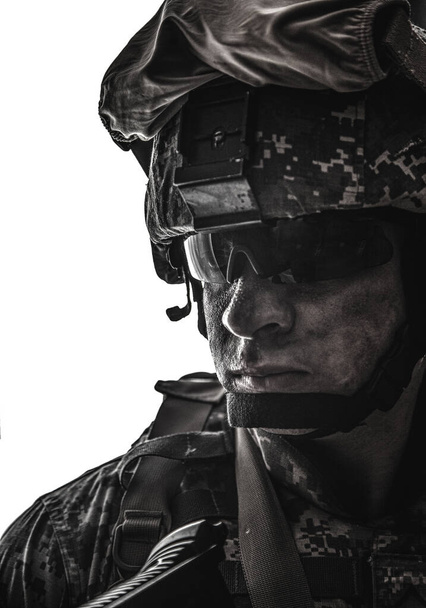 白い背景に分離したデジタル迷彩戦闘制服、戦闘ヘルメット、戦術的なサングラスの彩度の低い、カメラ目線で汚い顔をして現代的な軍歩兵兵士の肩の肖像画 - 写真・画像