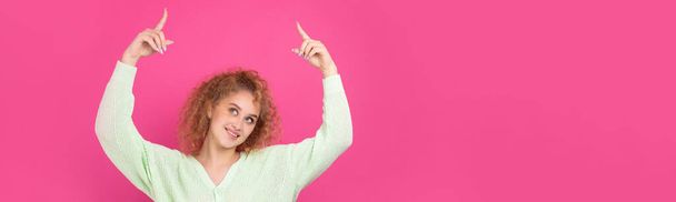 Egy fiatal lány göndör haj pontokat egy gesztussal a stúdió háttér. - Fotó, kép