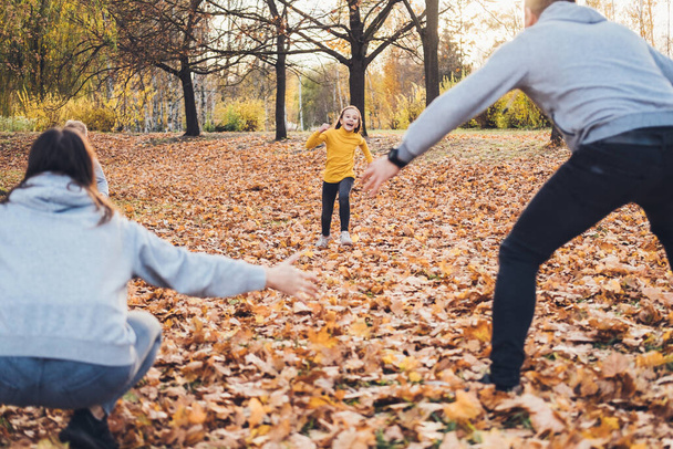 Girl running to mother and father who waiting with open arms, enjoying leisure time in autumn forest. Mother nature. Autumn forest. Happy family. - Foto, immagini