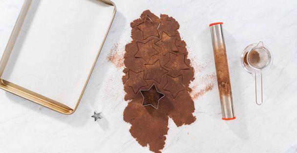 Flat lay. Cutting star-shaped chocolate graham crackers from the dough with a cookie cutter. - Photo, Image