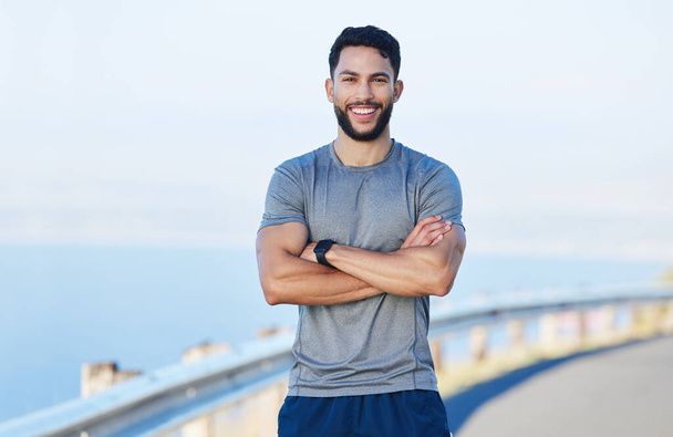 Man athlete, healthy and with cross arms, smile and stand happy outdoor for workout, warm up and wellness..Portrait, confident male and trainer ready for training, fitness and enjoy health exercise - Foto, Imagem