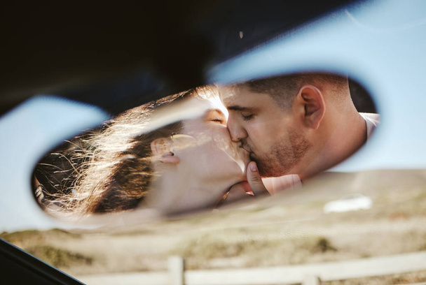 Kiss, mirror and couple on a road trip for holiday during marriage together. Young man and woman with love and affection going on vacation in Mexico and kissing while on a calm drive in nature. - Photo, Image