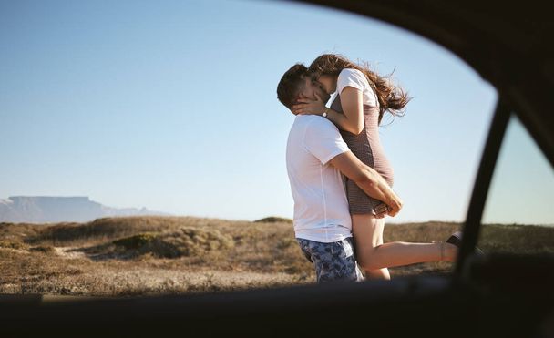 Поцілунок, любов і пара в дорозі з автомобілем за природою Каліфорнії протягом літа. Молодий чоловік і жінка цілуються під час подорожі з транспортом у сільській місцевості для пригод.. - Фото, зображення