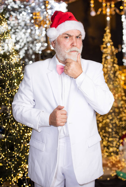 Holiday atmosphere. mature man white formal suit. serious businessman in event tuxedo. senior man santa christmas light illuminated background. bright and festive xmas mood. happy new year party. - Zdjęcie, obraz