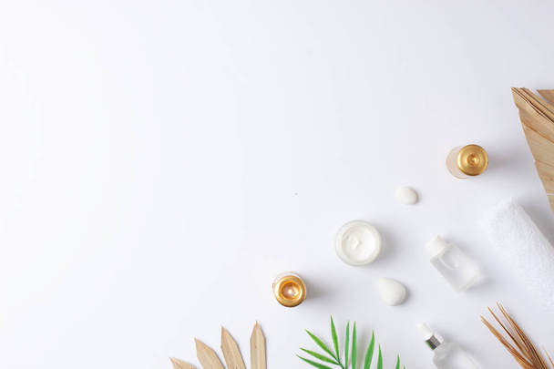 Beyaz arka planda kozmetik şişe, mum ve palmiye yaprağı ile kaplıca tedavisi. Düz yat, boşluğu kopyala - Fotoğraf, Görsel
