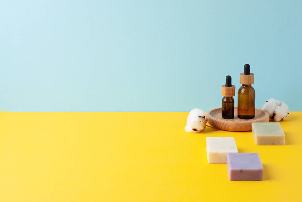 Kosmetische Hautpflegeprodukte mit Blumen und Seife auf blauem, gelbem Hintergrund. Nahaufnahme, Kopierraum - Foto, Bild