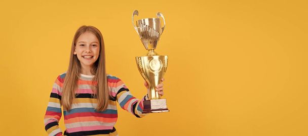 Glückliches Kind hält goldenen Pokal in der Hand. Leistungspreis. Schulerfolg feiern. Horizontales Poster mit isoliertem Kindergesicht, Banner-Header, Kopierraum - Foto, Bild